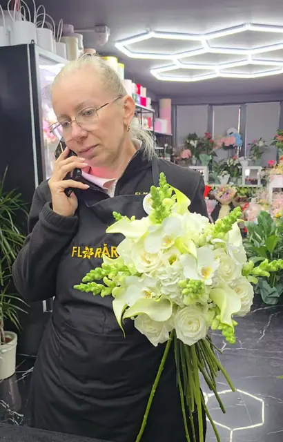 În florărie, cu un buchet alb de crini și trandafiri