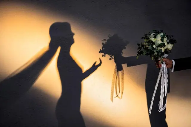Siluetele mirilor cu buchetele în lumină caldă